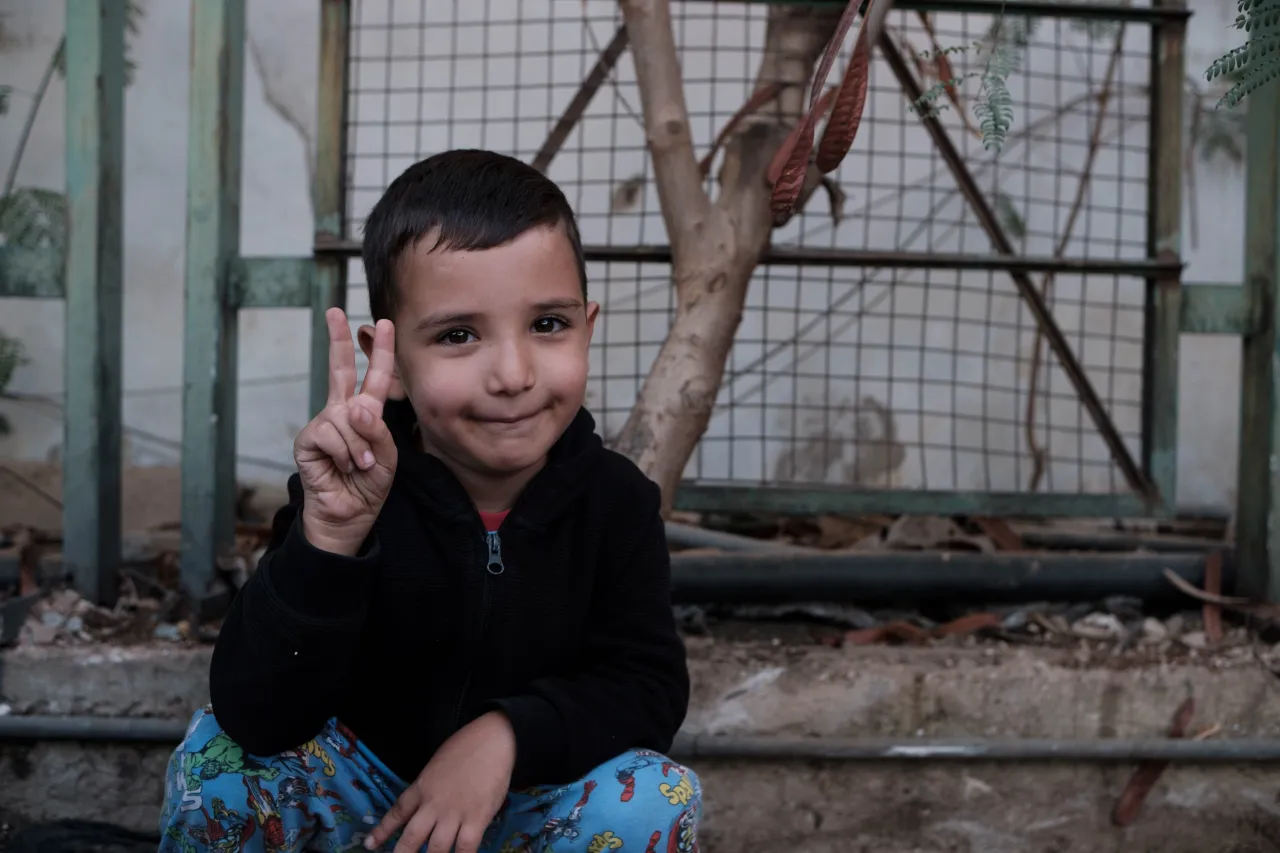 Ghadi sits on a step and makes a peace sign