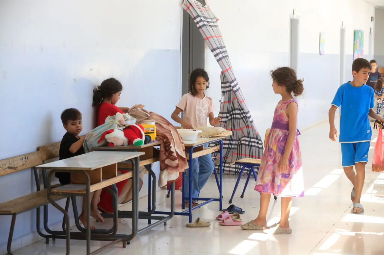 Children sitting and standing in a hallway where blankets have been distributed