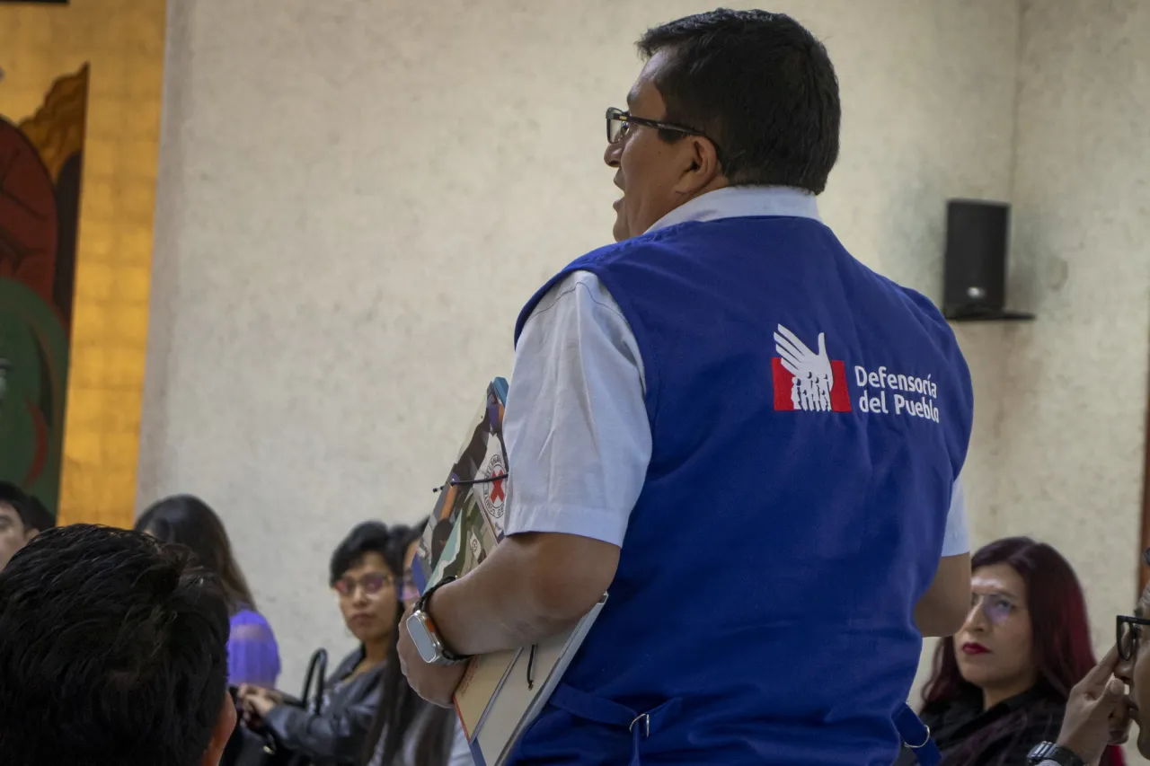 Personal de Defensoría sostiene una carpeta del CICR mientras habla a sus compañeros.