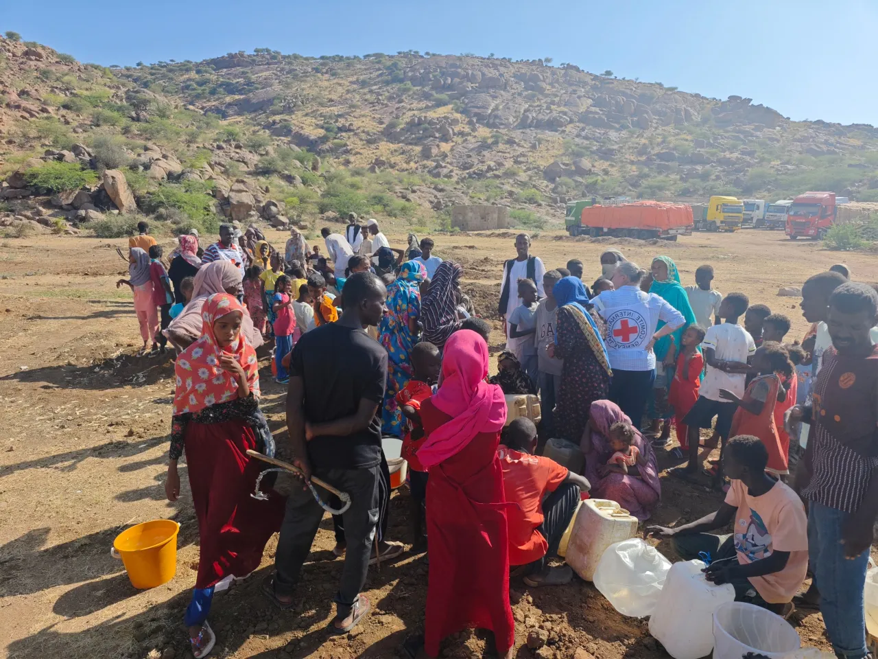 ICRC staff assist displaced families gathering for aid distribution in a rural, mountainous area, in Port Sudan.
