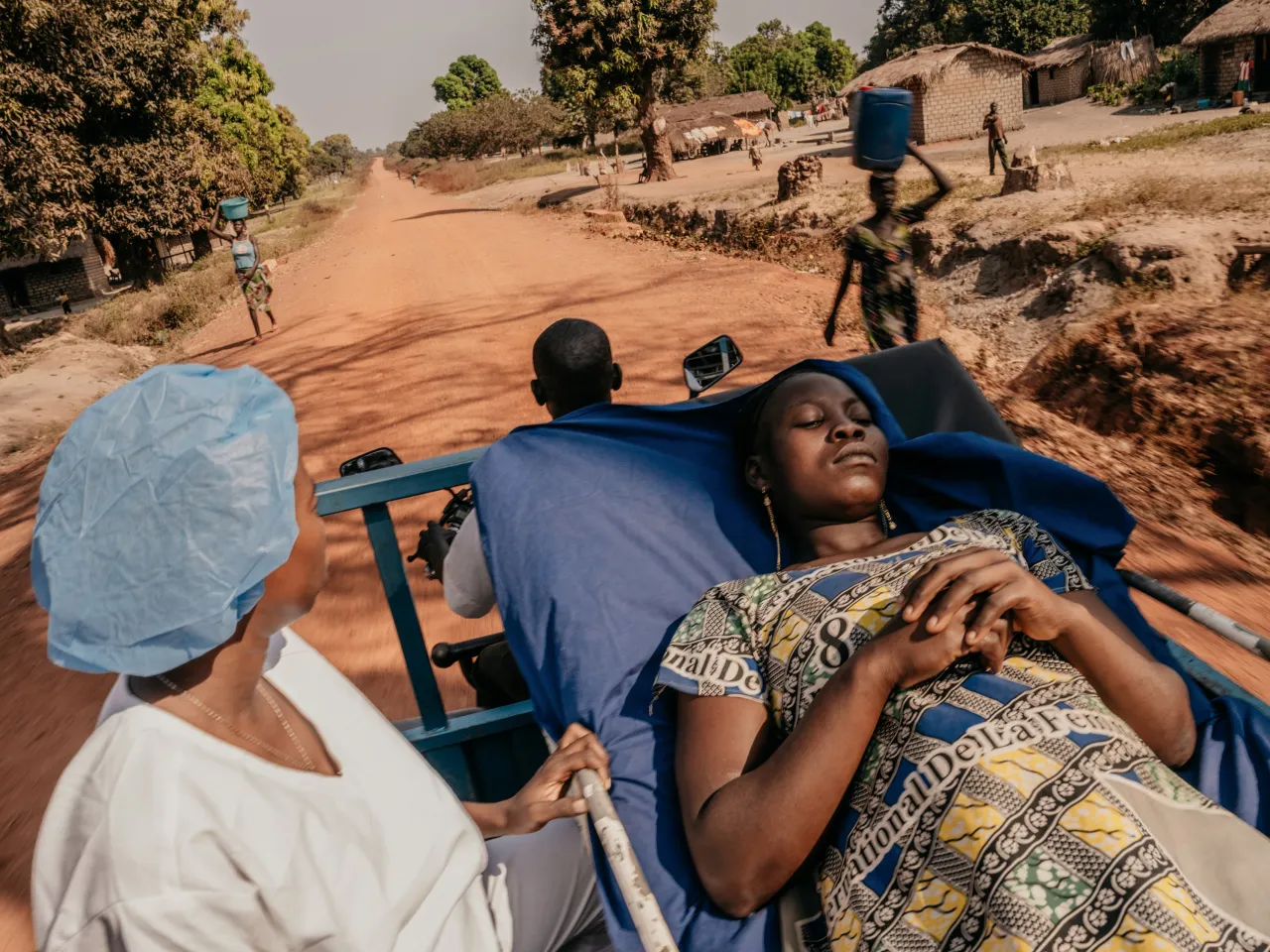 Nurses at the Doukouma health centre use a motorcycle ambulance to transport Bakote Kitiesa, illustrating how they move expectant mothers with complications from remote areas to seek healthcare at hospitals.  Doukouma, Central African Republic, 9th December 2024.