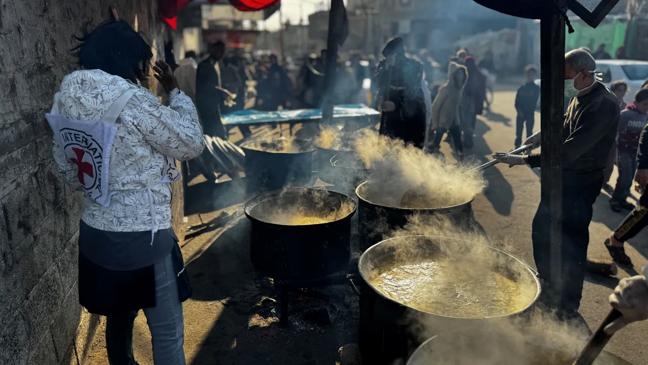 ICRC staff stands behind large vats of food steaming