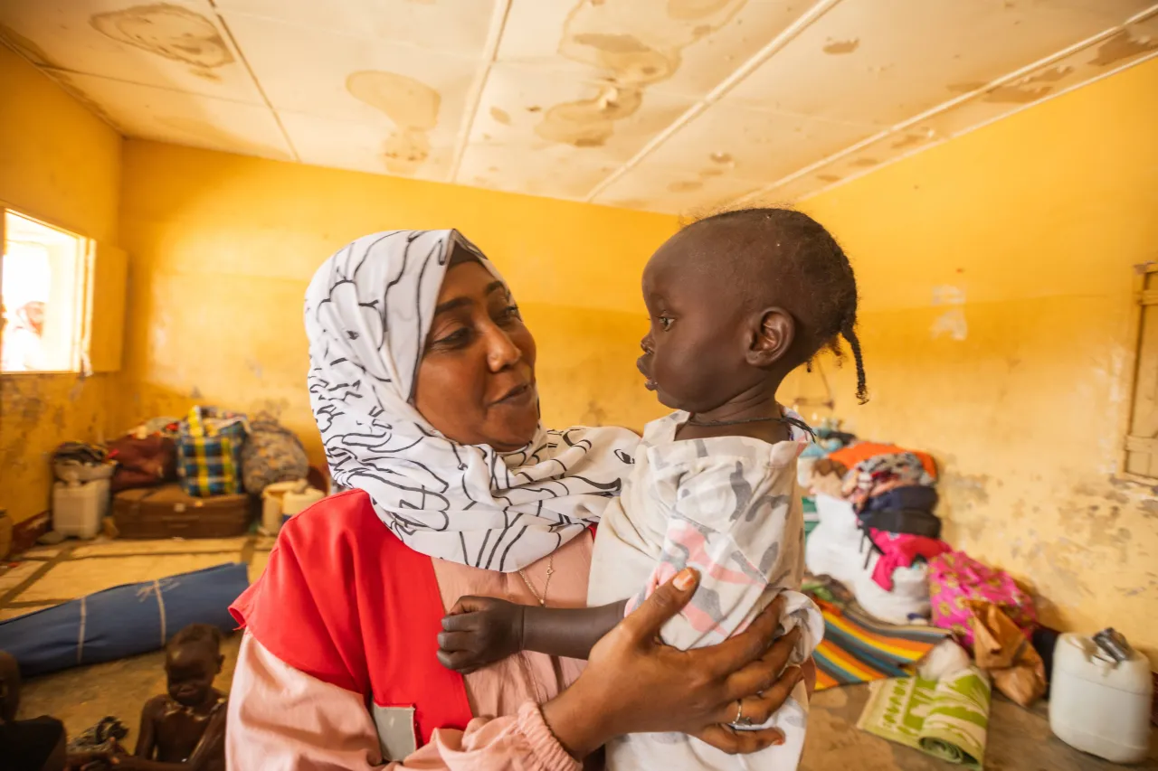 Wajdan Hassan Ahmed, SRCS volunteer, holds a young child in her arms