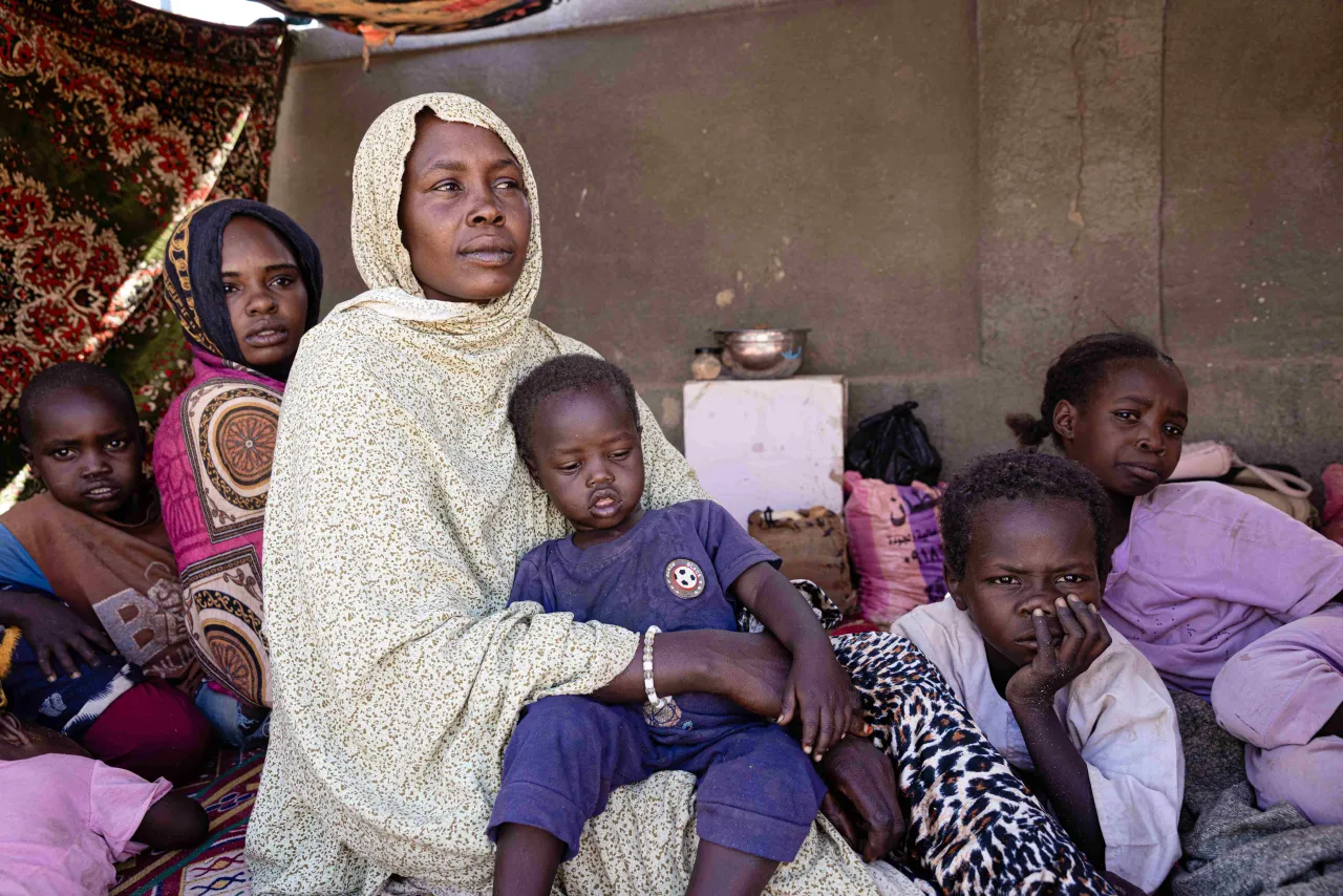 Khadija Adam Youssouf, Sudanese refugee in Tiné sits in a tent with a child on her lap and her other children surrounding her
