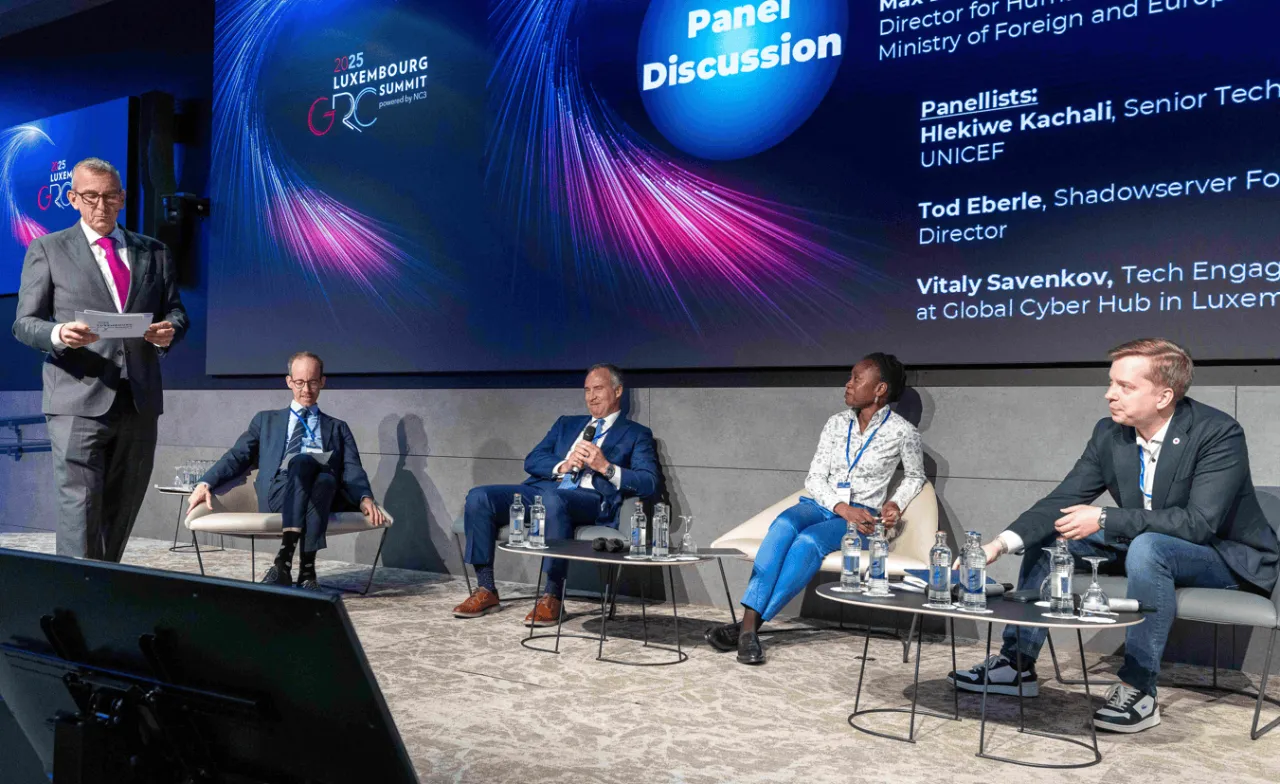 One moderator and four panelists sitting on stage