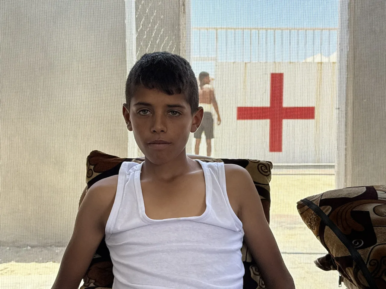 Hassam Syam, 17 years old, sitting in a chair at the field hospital in Gaza