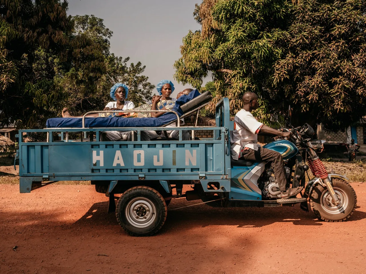 Nurses at the Doukouma Health Center use a motorcycle ambulance to transport Bakote Kitiesa, illustrating how they move pregnant women with complications from remote areas to seek treatment at hospitals.