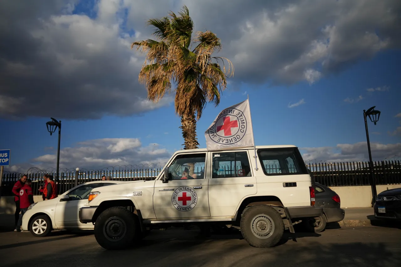 An ICRC vehicle displaying the Red Cross emblem and flag is parked along a coastal road in Lebanon during humanitarian operations amid escalating hostilities.