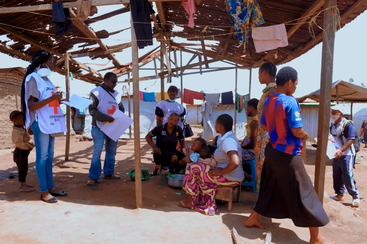 Red Cross volunteers conduct an Ebola awareness session with community members, including women and children, at a displacement site in the Democratic Republic of the Congo.