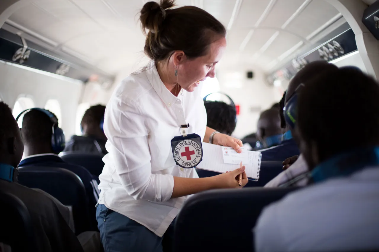 An ICRC staff member assists a released detainee during a humanitarian flight in South Sudan.