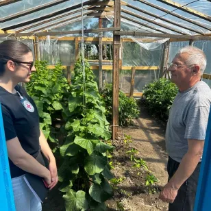 An ICRC staff member talks with a man in a greenhouse.