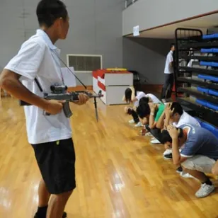 一个扮演士兵的男孩用一把玩具枪颐指气使地指着那些扮演战俘的学生们。之后，扮演红十字国际委员会代表的年轻女孩将前往拘留场所探视这些“战俘”。