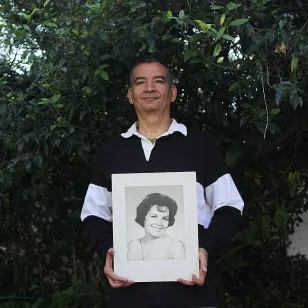 Un familiar de doña Cony sostienes un retrato 