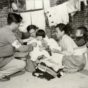 Red Cross workers providing clothing to war refugees (2 November 1950)