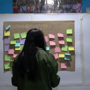 Participante mira un mural con post it de un ejercicio grupal.