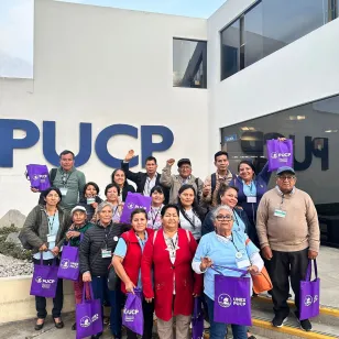 Familiares en foto grupal con pared de fondo que dice: PUCP.