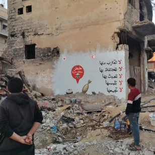 ICRC mural on the walls of a half-destroyed building giving information about unexploded ordinance