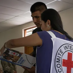 Una trabajadora del CICR entrega un material impreso del CICR a un militar.