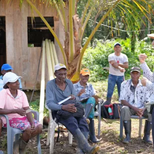 Una comuindad sentada que está escuchando a una persona del Comité Internacional de la Cruz Roja, que está frente a la comunidad dialogando con ellos.