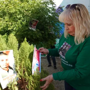 Una familiar coloca una foto en un árbol