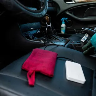 The interior of a car shows personal items, including a cloth and a phone, placed on the seat