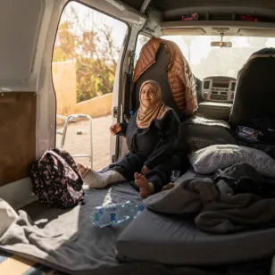 Saada sits inside a van adapted as living space, with mattresses and personal belongings arranged around her, where she lives with her extended family in Lebanon.