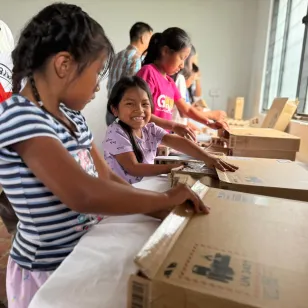 Niñas abren una caja sonriendo.