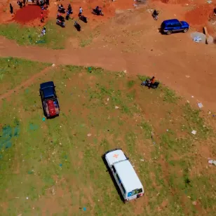 Aerial view of a Red Cross response site in the Democratic Republic of the Congo, showing vehicles on red earth terrain near a community area during Ebola operations.