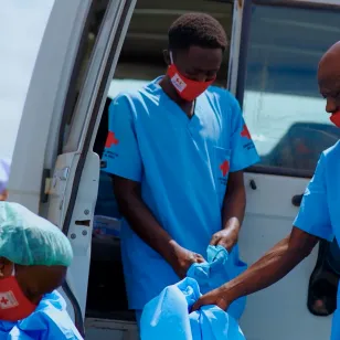 Red Cross volunteers in blue protective clothing unload equipment from a vehicle in preparation for Ebola response activities in the Democratic Republic of the Congo.