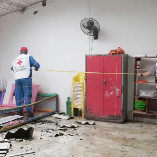 ICRC staff assess damage inside a school in Chocó, Colombia, following an earthquake. Debris is scattered across the floor and part of the roof has collapsed.