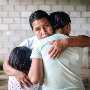 Mujer abrazando a sus dos hijas con una expresión de dolor y tristeza ante la desaparición de su esposo