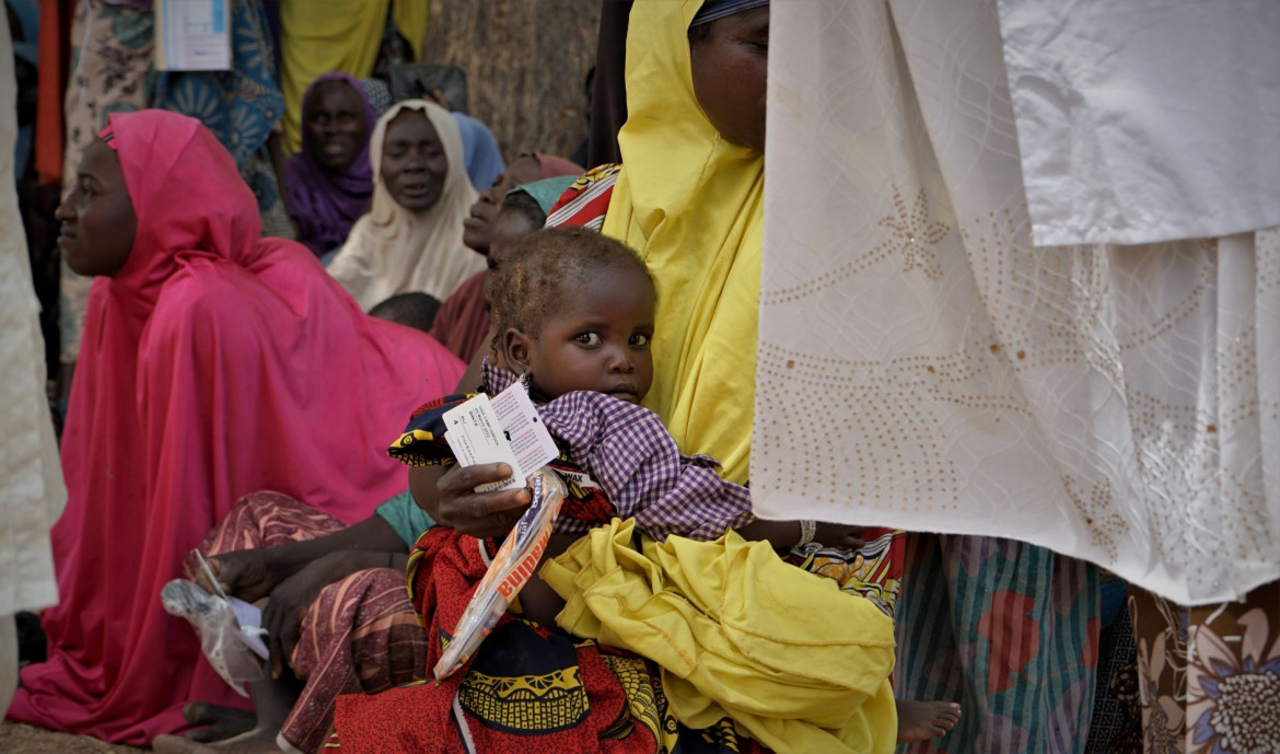 A young child holds on to her mother as they wait for their turn at the distribution centre 