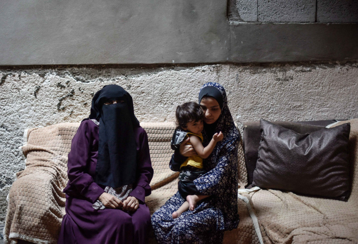 Hanan sitting with Mohammed’s wife, Dua’, and their son, Nehad, in their home in Gaza City.