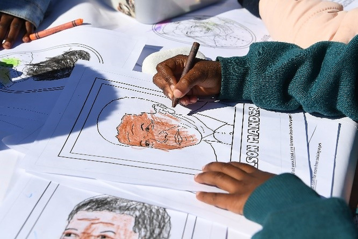 Children are colouring-in pages that have Mandela's faces on them