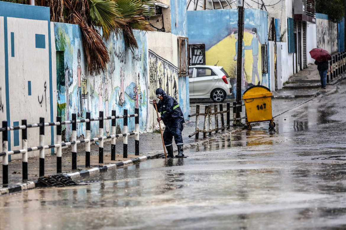 عاملٌ في البلدية يفتح أغطية مصارف المياه في أحد شوارع غزة حتى لا تفيض بالمياه جراء الهطول الغزير للأمطار فيها. 