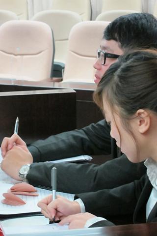 广州大学队的第一场比赛与吉林大学队对阵。作为辩方的王旭东（后一）和李琳（前一）在对方发言时，飞快地做着笔记，为接下来的抗辩环节做准备。研究法律理论的王旭东希望将来可以当一名大学老师。