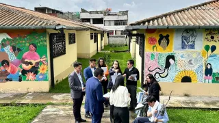 Jóvenes vestidos en un juego de roles interactúan en un jardín frente a unos murales.