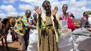 Woman at Ethipoian Red Cross Society distribution of food supplies and essential household items waves to the camera