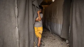 Child next to a tent in ICRC camp in Greece