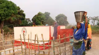 Une bénéficiaire devant le forage construit.