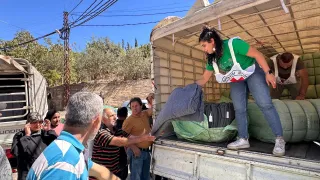 ICRC worker stands at the back of a lorry to unload blankets and essential items