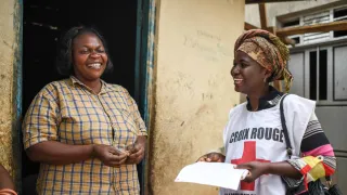 ICRC delegate speaking to a smiling woman in a doorway