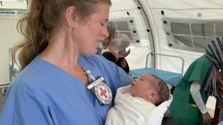 An ICRC nurse holding a newborn in her arms.