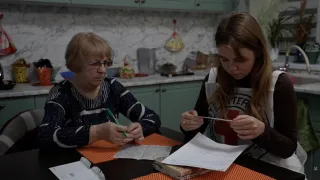 Madre de un prisionero de guerra sentada en un tanle con personal del CICR, escribiendo una carta a un ser querido.