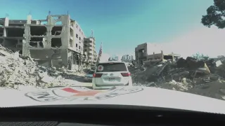 ICRC Landcruisers driving past fallen buildings
