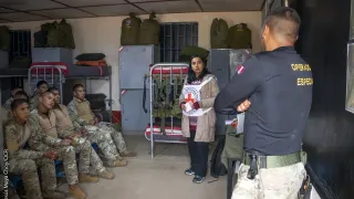 Una trabajadora del CICR explica el DIH a personal militar en un cuarto de tropa.