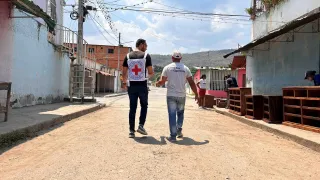 En Magdaleno, estado Aragua, uno de los participantes del proyecto de emprendimiento está caminando por la calle conversando con un trabajador del CICR.