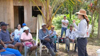 Una comuindad sentada que está escuchando a una persona del Comité Internacional de la Cruz Roja, que está frente a la comunidad dialogando con ellos.