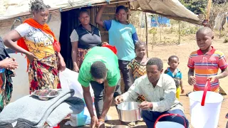 Família de pessoas deslocadas mostra baldes e outros artigos essenciais.