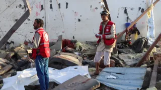 Two Red Crescent workers stand amidst the wreckage caused by an explosion